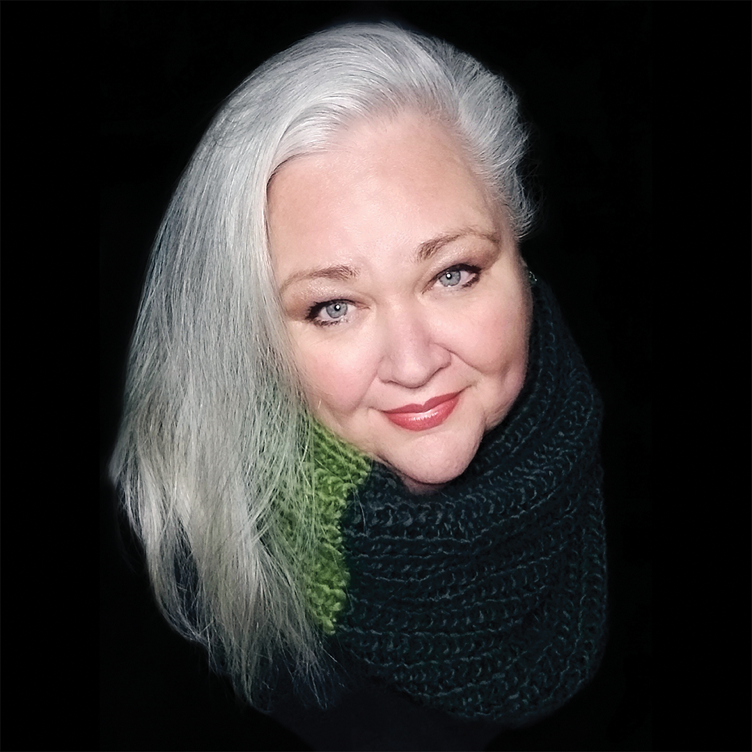 StephanieBlythe_1x1 A woman with white, mid-length hair swipt to the side gazes into the camera with a soft, red-lined smile.